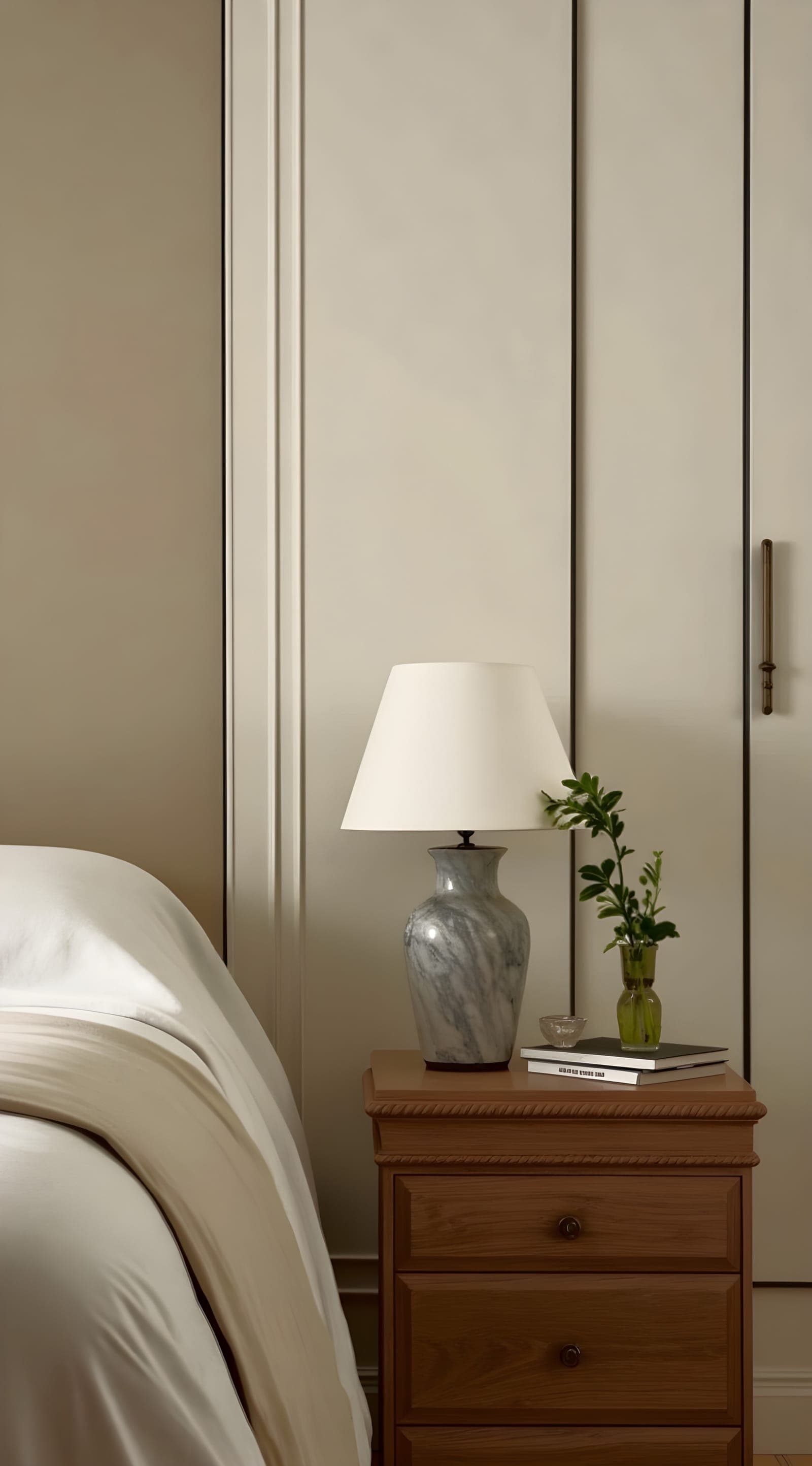 A marble table lamp on a bedside table beside a small green sprig