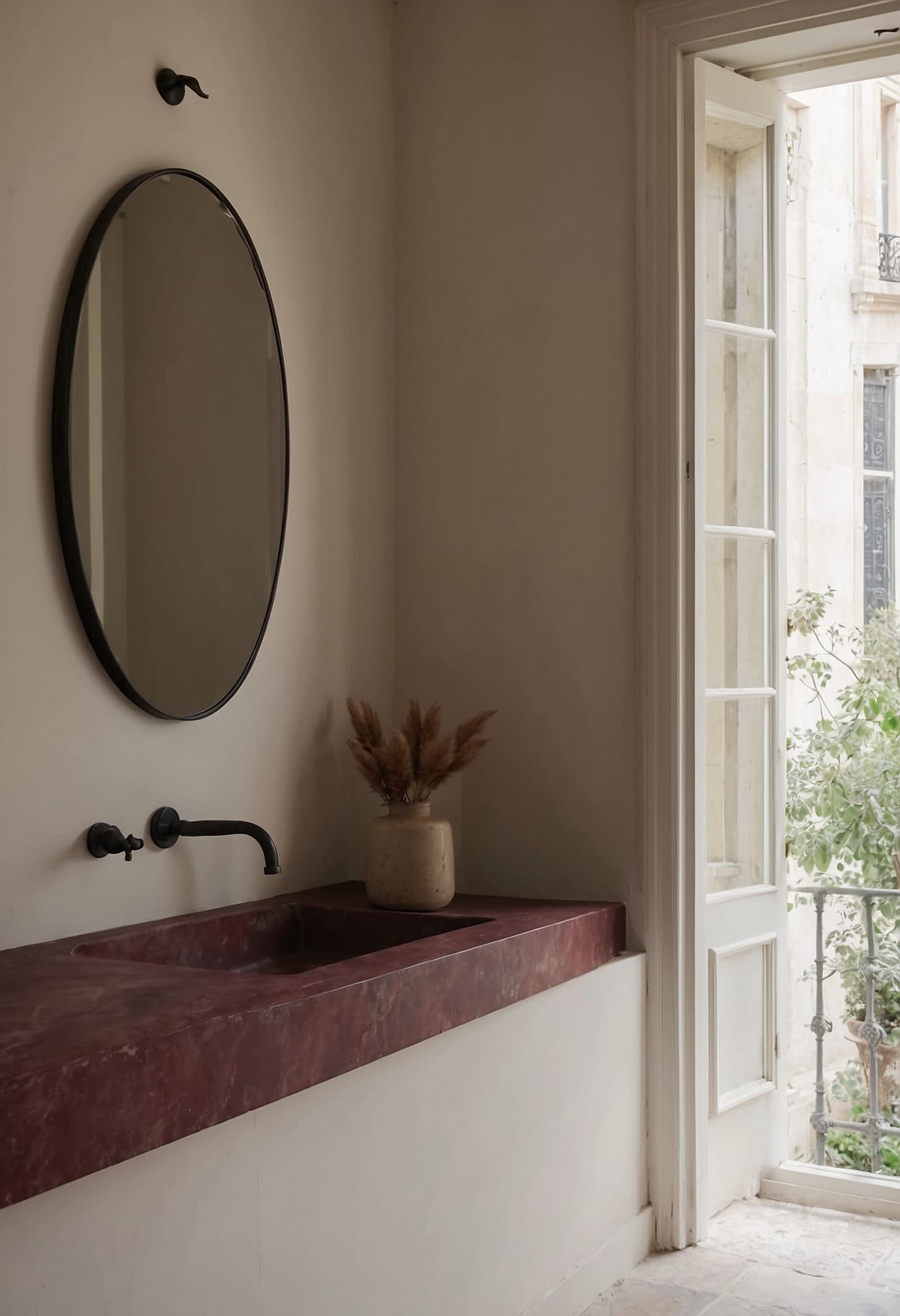 A pale limestone vanity ledge with a ceramic basin and single glass vase against limewashed plaster