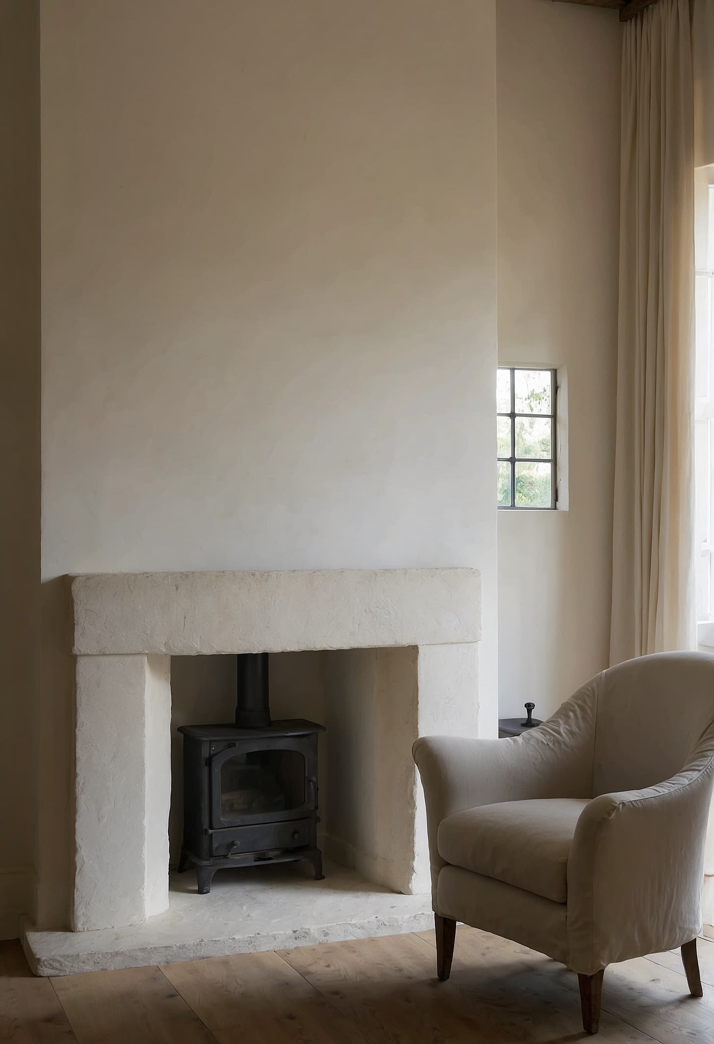 Wide Georgian living room, limestone fireplace, tall sash windows, linen-covered furniture, bare plaster walls